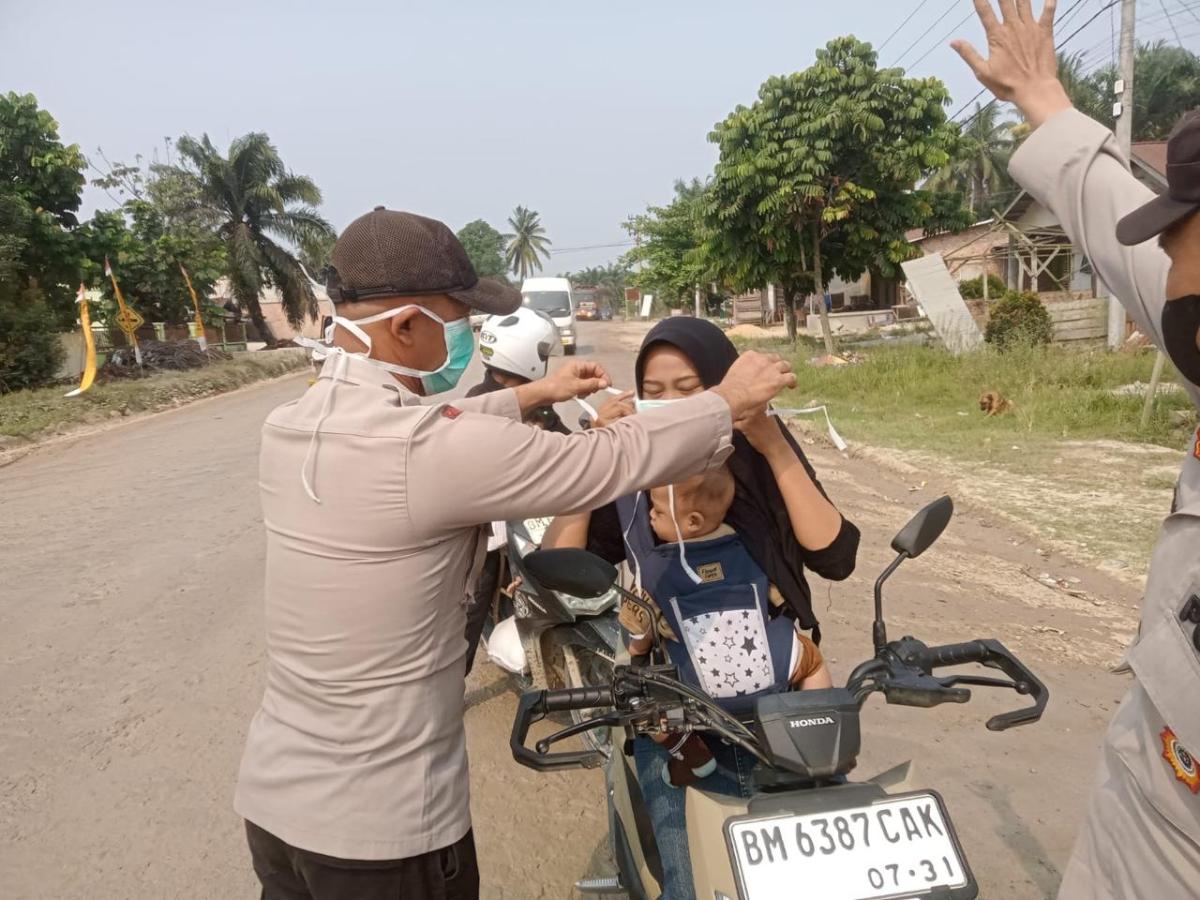 Peduli Dampak Kabut Asap Karhutla, Polsek Langgam Bagikan Masker kepada Warga
